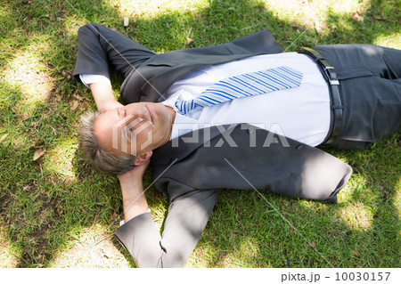 Businessman lying on grass Businessman lying on grass 10030157