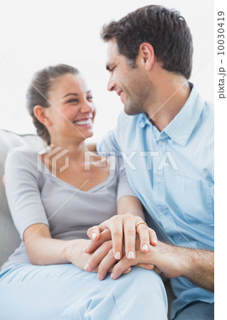 Excited couple looking at each other on the couch 10030419