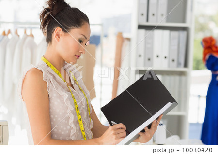 Female fashion designer looking at folder 10030420