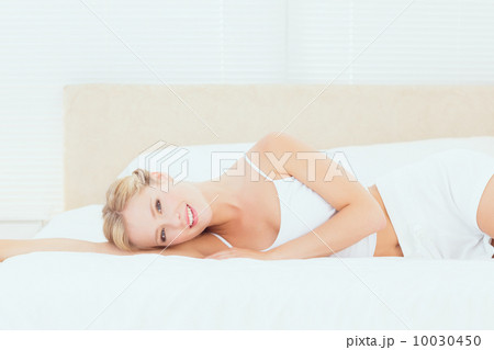 Pretty blonde lying on her bed smiling at camera 10030450
