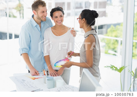 Interior designer showing colour wheel to happy young clients Interior designer showing colour wheel to happy young clients 10030763