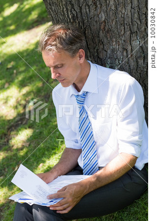 Businessman reviewing documents in park 10030842
