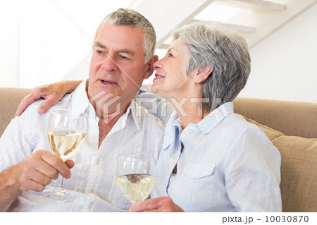 Senior couple sitting on couch drinking white wine Senior couple sitting on couch drinking white wine 10030870