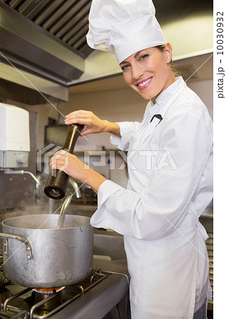 Smiling female cook preparing food in kitchen 10030932