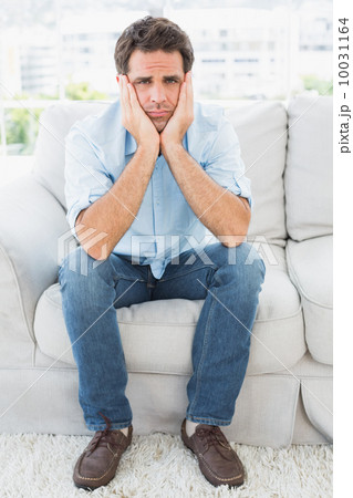 Upset man sitting on the couch looking at camera Upset man sitting on the couch looking at camera 10031164