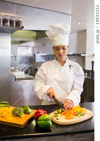 Female chef cutting vegetables in kitchen Female chef cutting vegetables in kitchen 10031552
