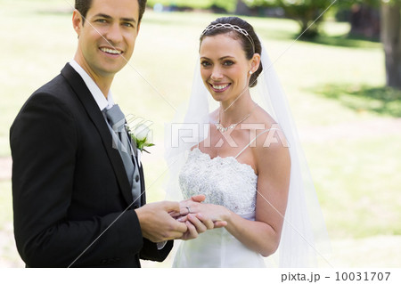 Groom placing ring on brides finger at park 10031707