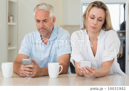 Bored couple sitting at the counter texting 10031982