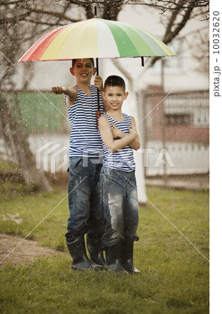 two boys with rainbow umbrella in park two boys with rainbow umbrella in park 10032620