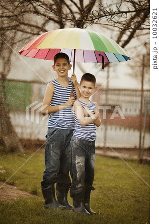 two boys with rainbow umbrella in park 10032621
