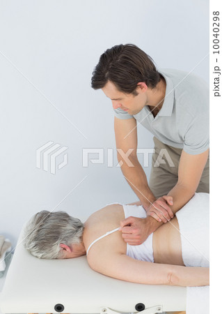 Male physiotherapist massaging a senior woman's back 10040298