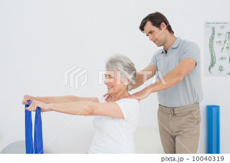 Male therapist assisting senior woman with exercises 10040319