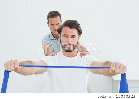 Male therapist assisting young man with exercises 10040323