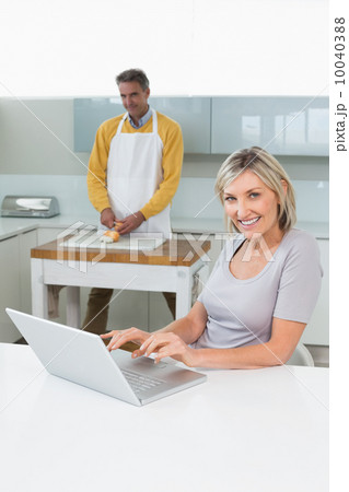 Woman using laptop and man chopping vegetables Woman using laptop and man chopping vegetables 10040388