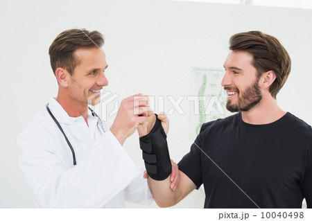 Male physiotherapist examining a young man's wrist Male physiotherapist examining a young man's wrist 10040498