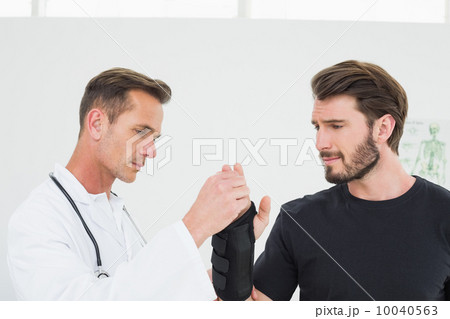 Male physiotherapist examining a man's wrist 10040563