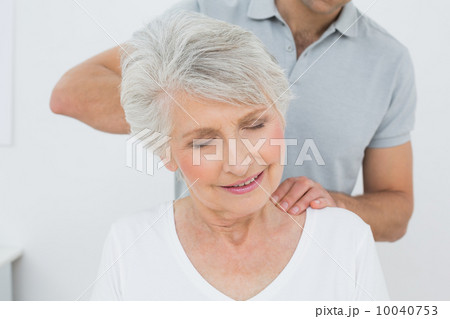 Male physiotherapist massaging a senior woman's neck 10040753