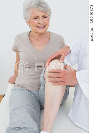 Displeased senior woman getting her knee examined Displeased senior woman getting her knee examined 10040878