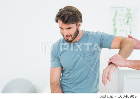 Male physiotherapist examining a young man's arm 10040909