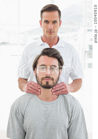 Male therapist massaging a young man's neck Male therapist massaging a young man's neck 10040910