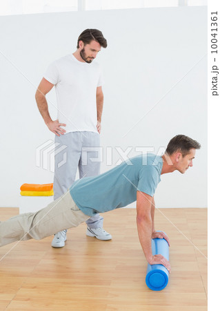 Physical therapist watching young man do push ups Physical therapist watching young man do push ups 10041361