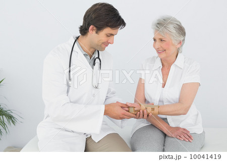 Male physiotherapist examining a senior woman's wrist 10041419