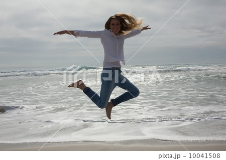 Full length of a casual woman jumping at beach Full length of a casual woman jumping at beach 10041508