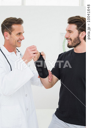Male physiotherapist examining a young man's wrist Male physiotherapist examining a young man's wrist 10041648