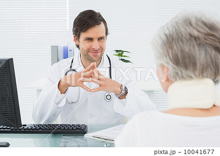 Smiling doctor listening to senior patient at medical office 10041677