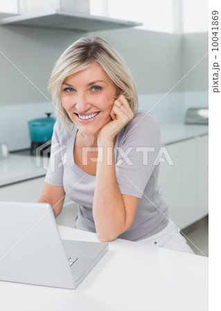 Casual happy woman with laptop in kitchen 10041869