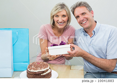 Man giving a happy woman a birthday gift beside cake Man giving a happy woman a birthday gift beside cake 10041883