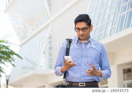 confused looking indian business male on a phone with office bac 10043575
