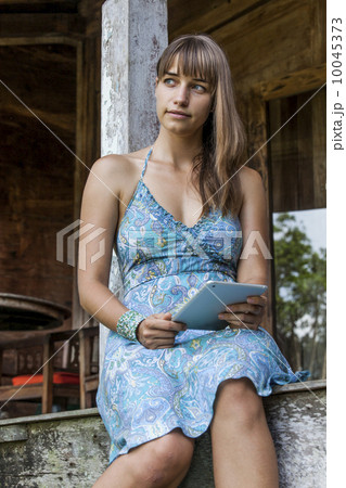 A young caucasian woman sitting and reading in a country house 10045373