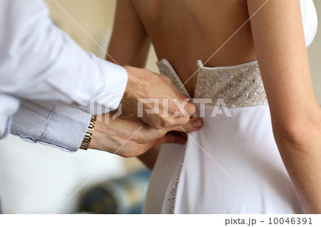 Groom helping birde to put wedding dress on 10046391