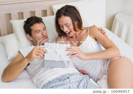 Couple with gift box lying together in bed 10046957