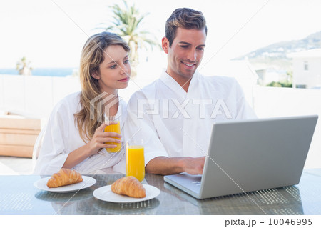 Couple using laptop on breakfast table 10046995
