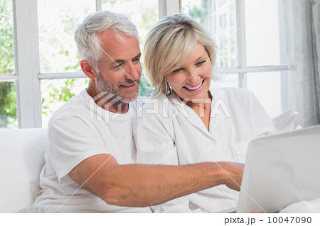 Happy mature couple using laptop in bed 10047090