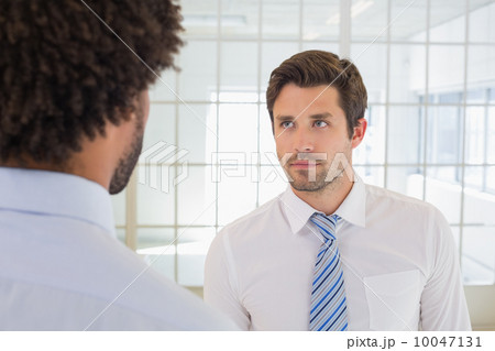 Serious businessmen looking at each other in office Serious businessmen looking at each other in office 10047131