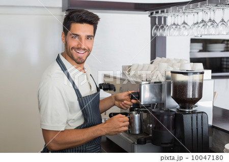 Waiter smiling and making cup of coffee at coffee shop 10047180