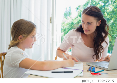 Woman with laptop assisting daughter in homework Woman with laptop assisting daughter in homework 10047215