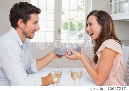 Man giving happy woman a gift box at home 10047217