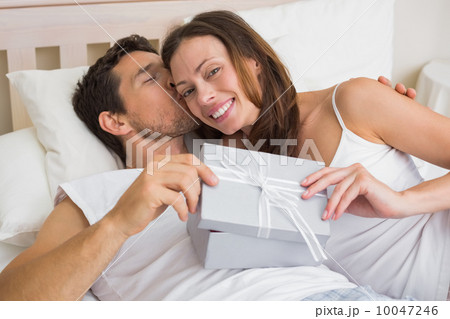 Relaxed couple with gift box lying together in bed Relaxed couple with gift box lying together in bed 10047246