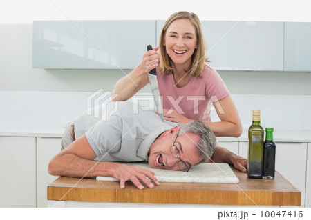 Happy woman holding knife to man's neck in kitchen Happy woman holding knife to man's neck in kitchen 10047416