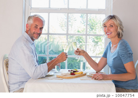 Side view portrait of a mature couple toasting drinks over food Side view portrait of a mature couple toasting drinks over food 10047754
