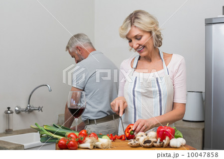 Happy mature couple preparing food together in kitchen Happy mature couple preparing food together in kitchen 10047858