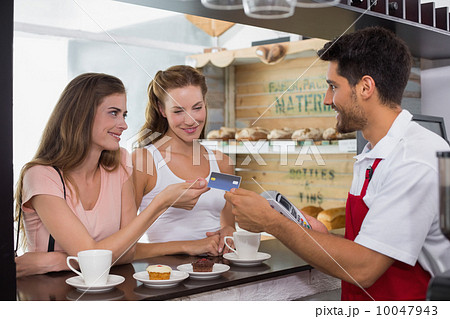 Friends with woman holding out credit card at coffee shop 10047943