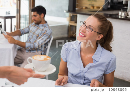 Smiling woman receiving coffee in coffee shop Smiling woman receiving coffee in coffee shop 10048096