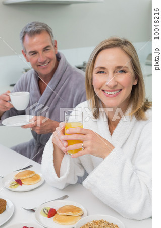 Smiling couple with orange juice and coffee in kitchen Smiling couple with orange juice and coffee in kitchen 10048216