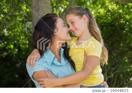 Mother and daughter rubbing noses in park 10048625