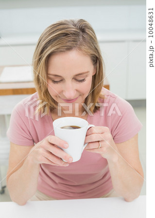 Eelaxed young woman having coffee in kitchen 10048631